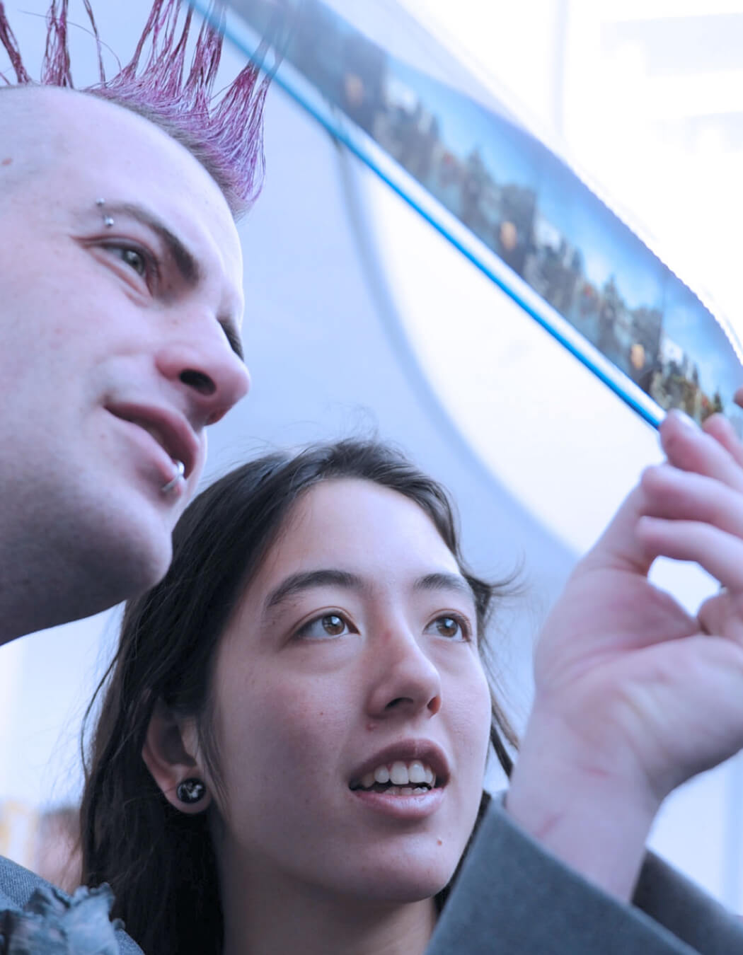 a guy and girl close up, they are looking and pointing at something in amazement