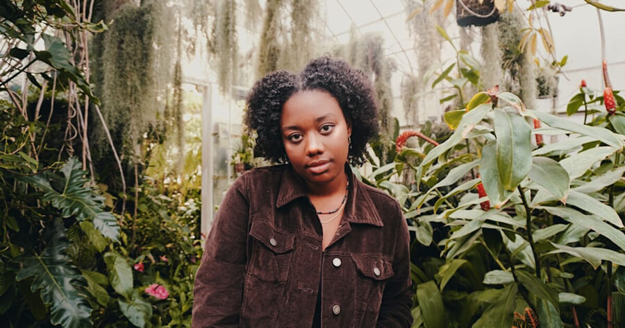 Alayshia Baggett looks into the camera in front of a tropical background.