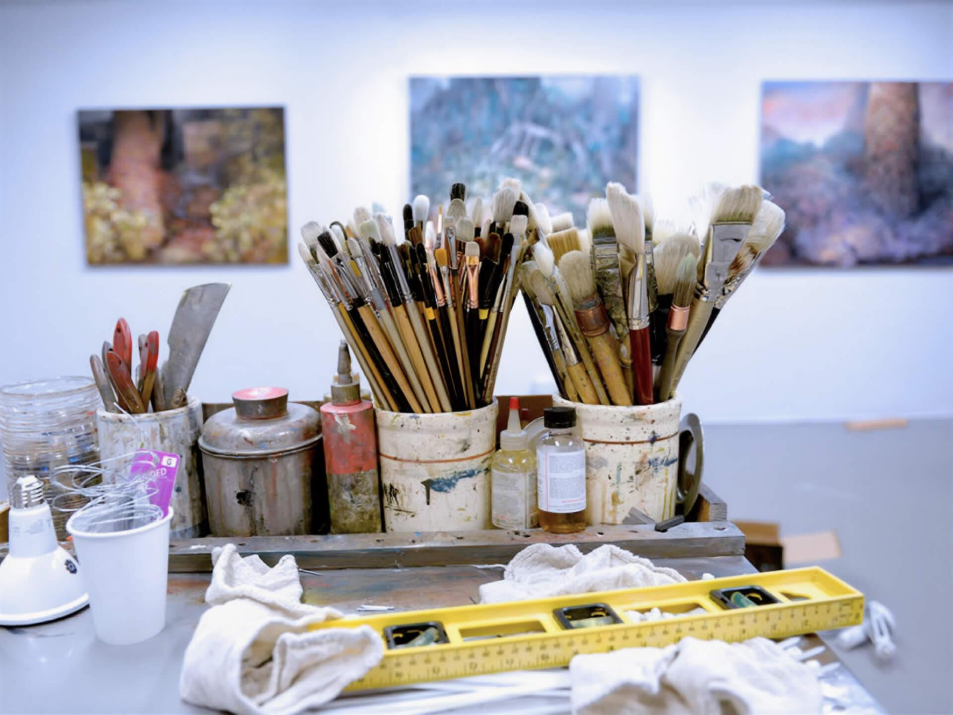 Two cups full of paint brushes in a bright art studio 