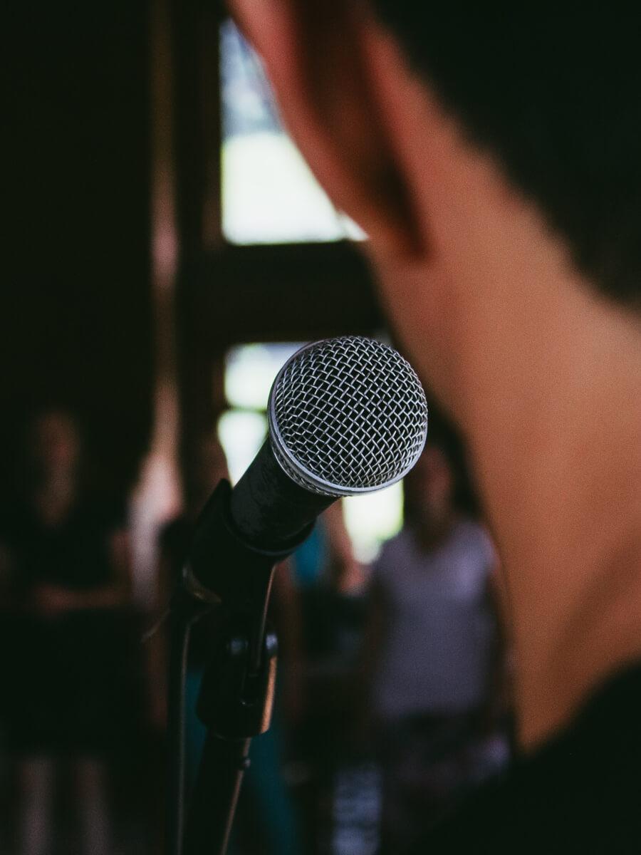 Person speaking into a microphone in front of a crowd