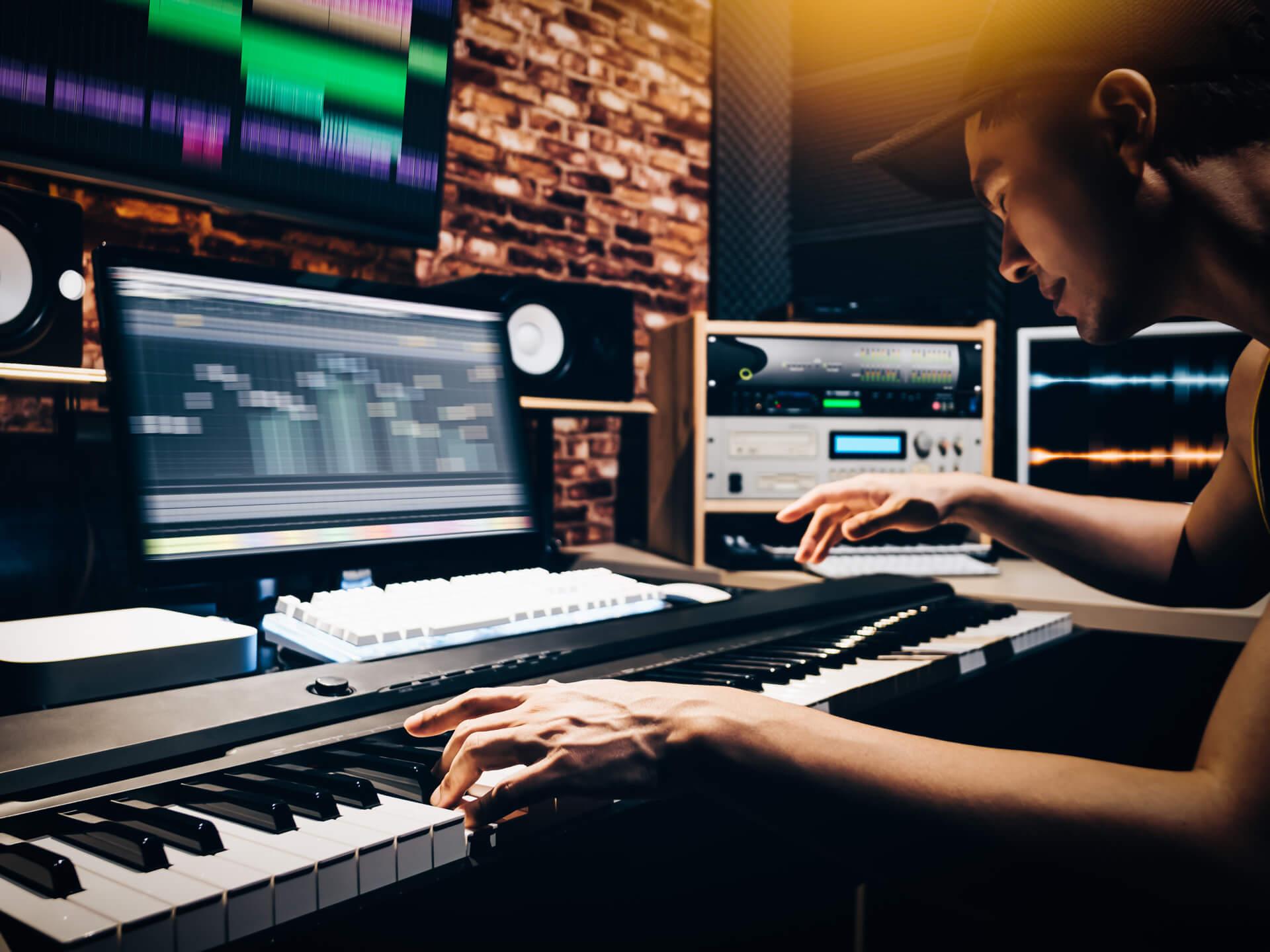 Asian man composing song on a keyboard in a studio