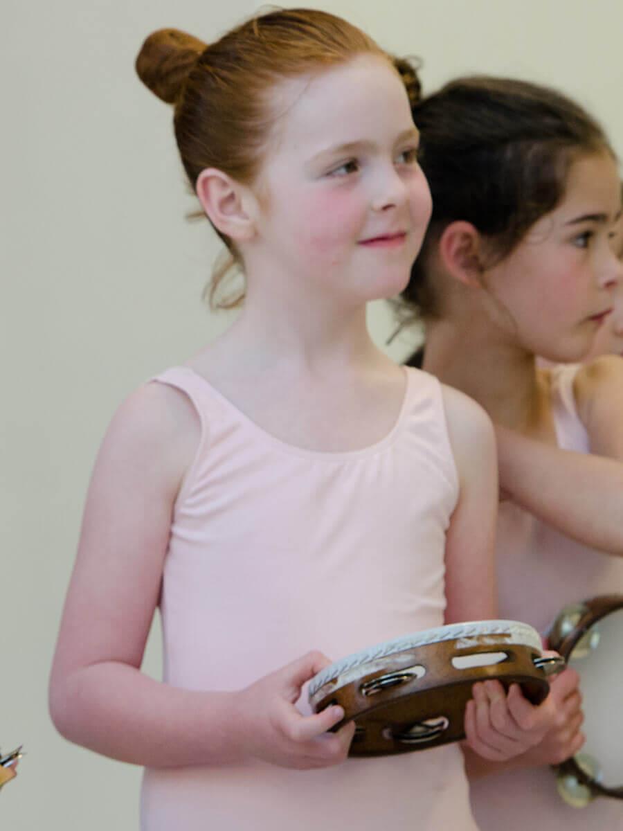 Young female pre-ballet student holding a tambourine