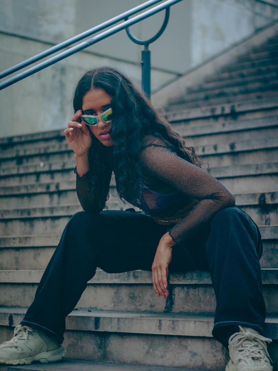 woman of color with sunglasses sitting on park steps
