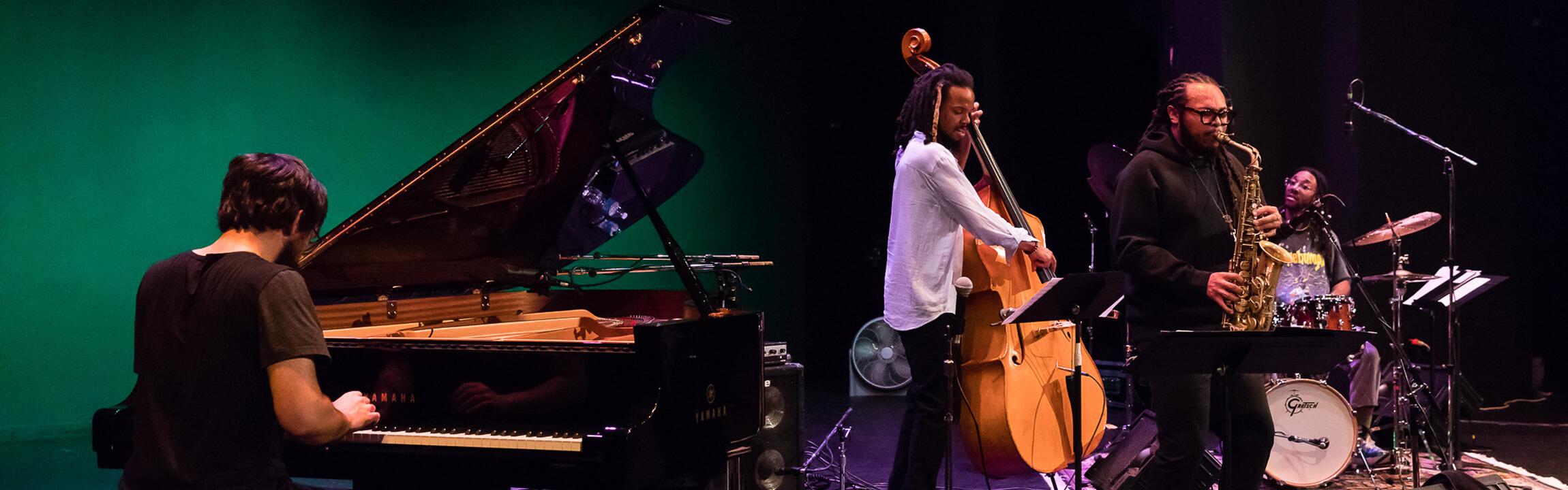 4 men playing jazz including piano double bass saxophone and drums