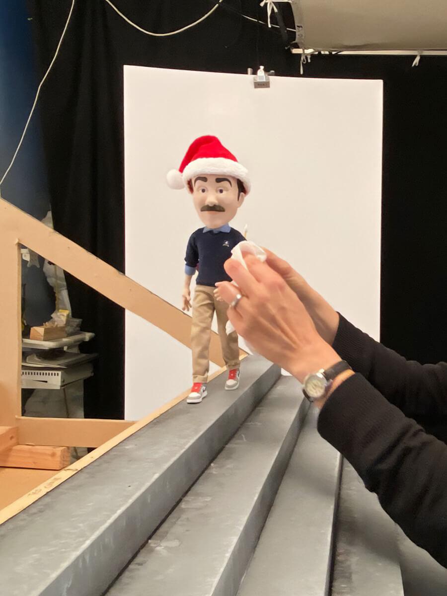 Puppeteer working on a Ted Lasso puppet that's wearing a Santa Clause hat