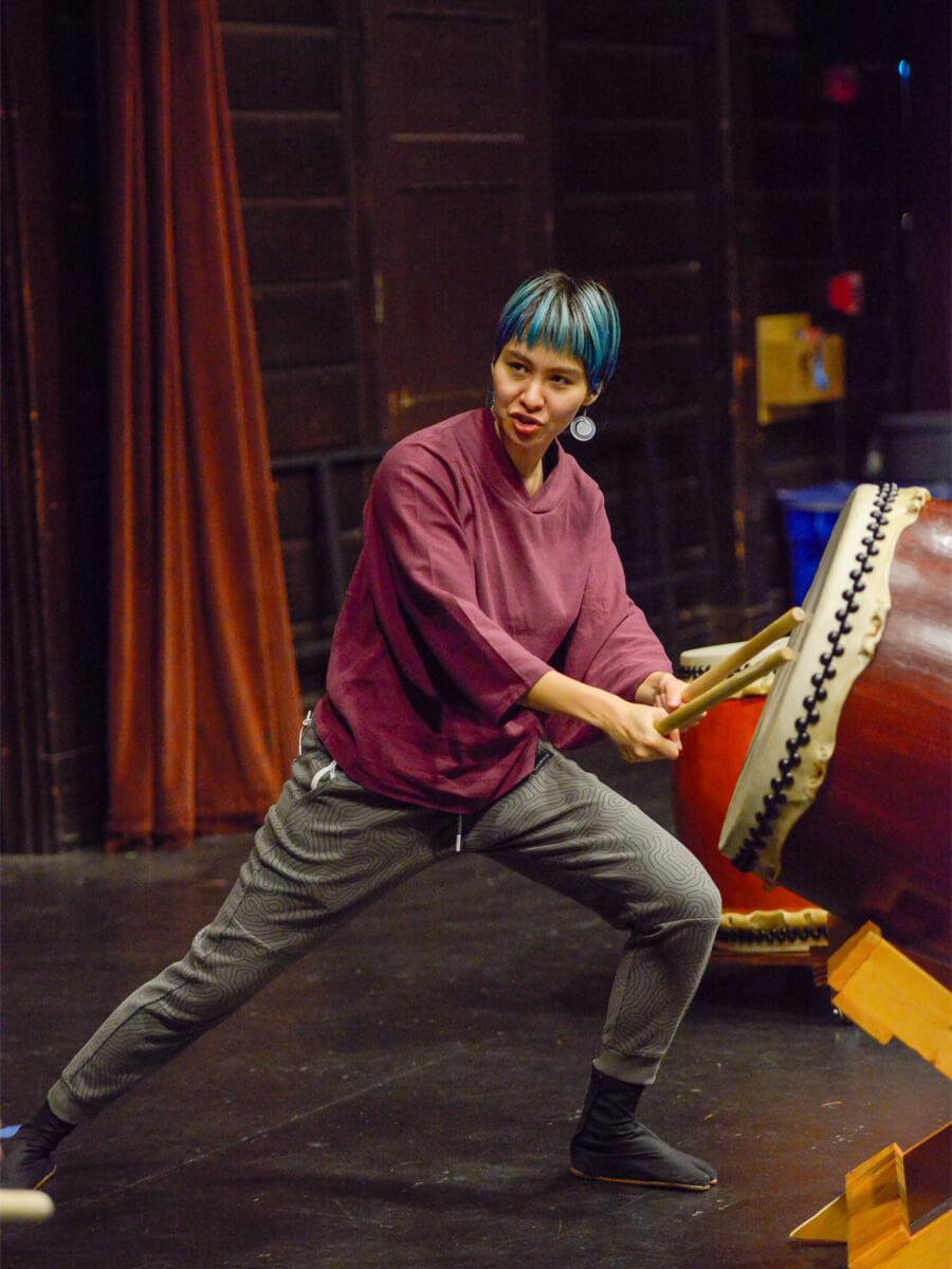 woman of Asian descent demonstrating taiko drums