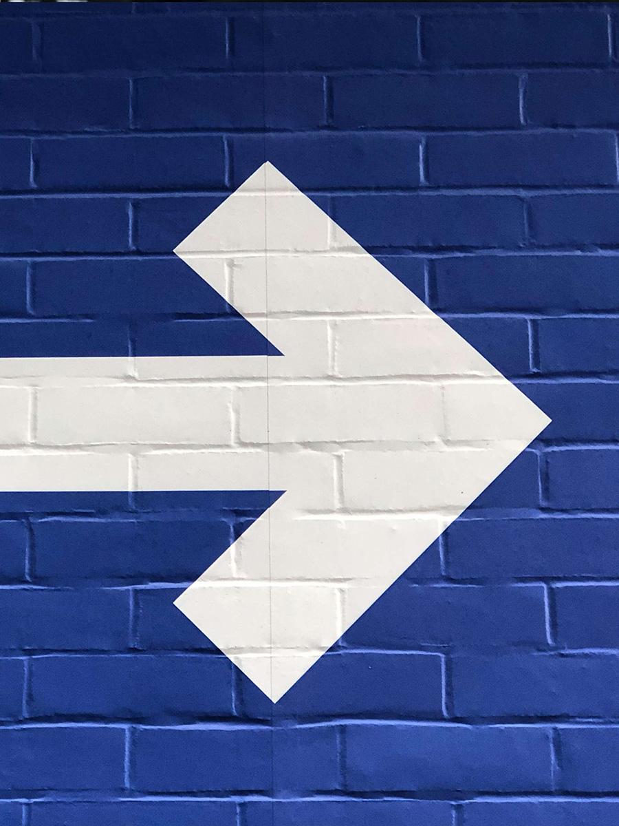 White arrow painted on blue painted brick