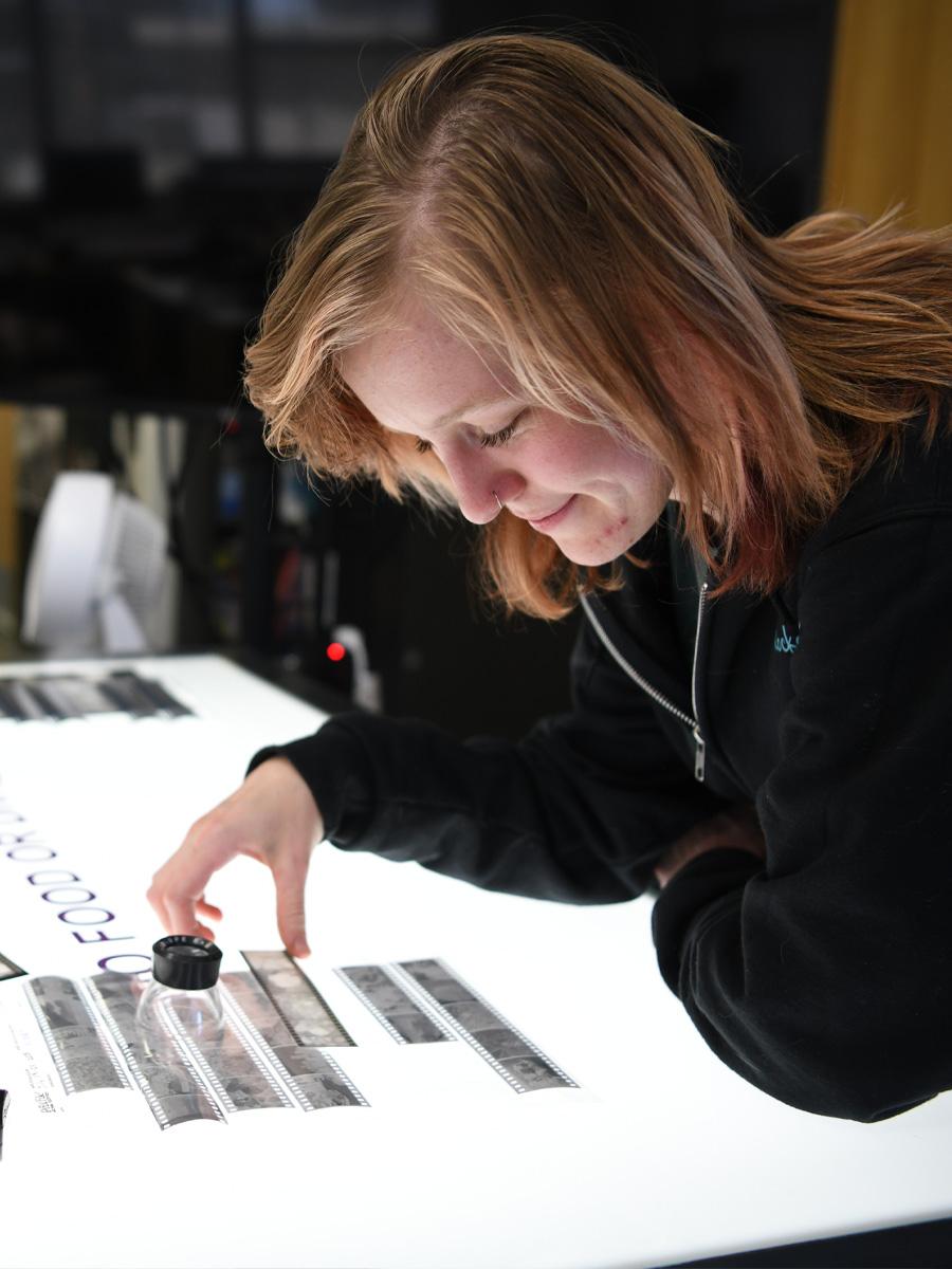 Photo student over a light table looking at negatives. 