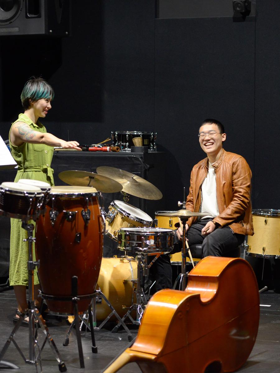 Musicians on stage with bass up front and the instructor directing the bass player.