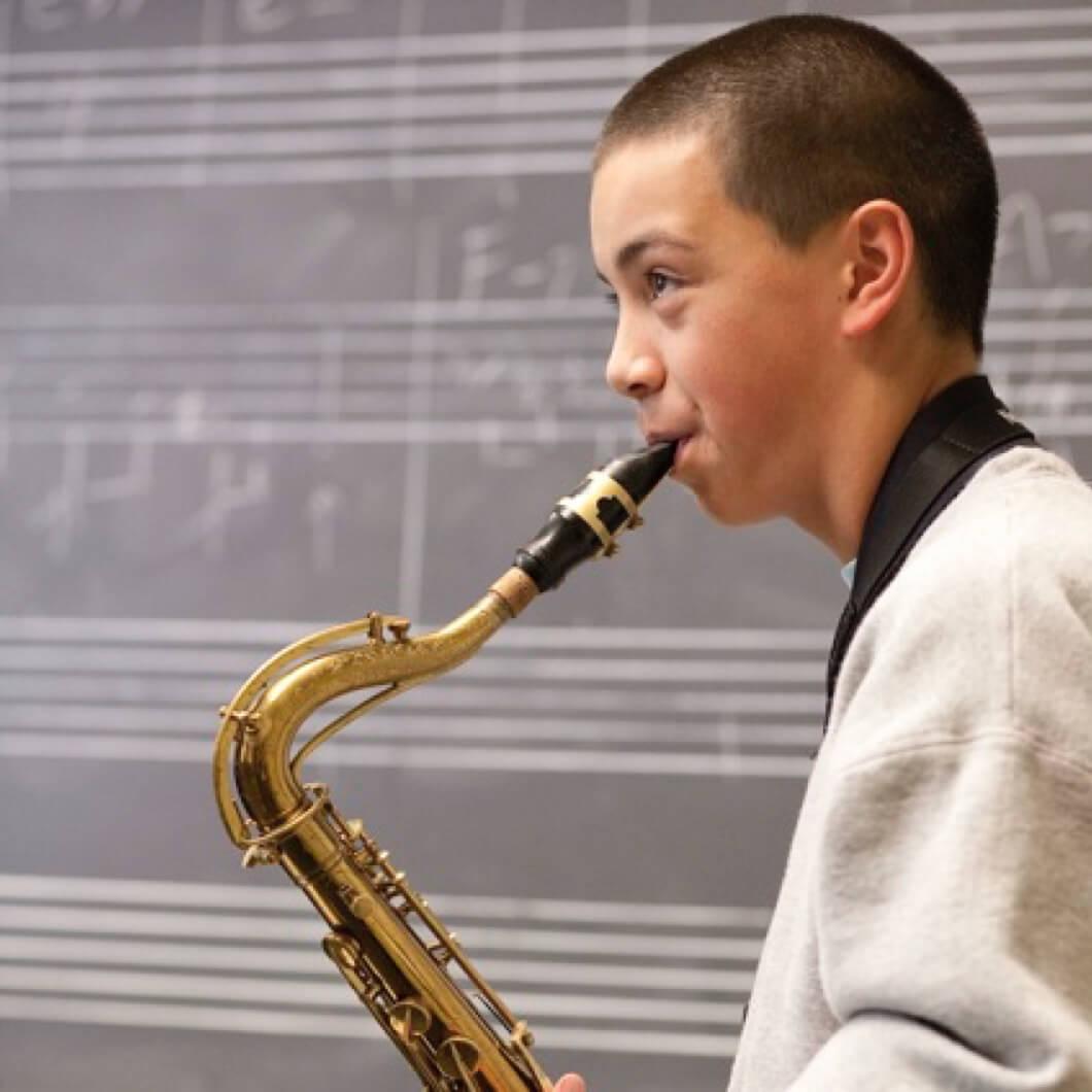 Student playing a saxophone in a classroom