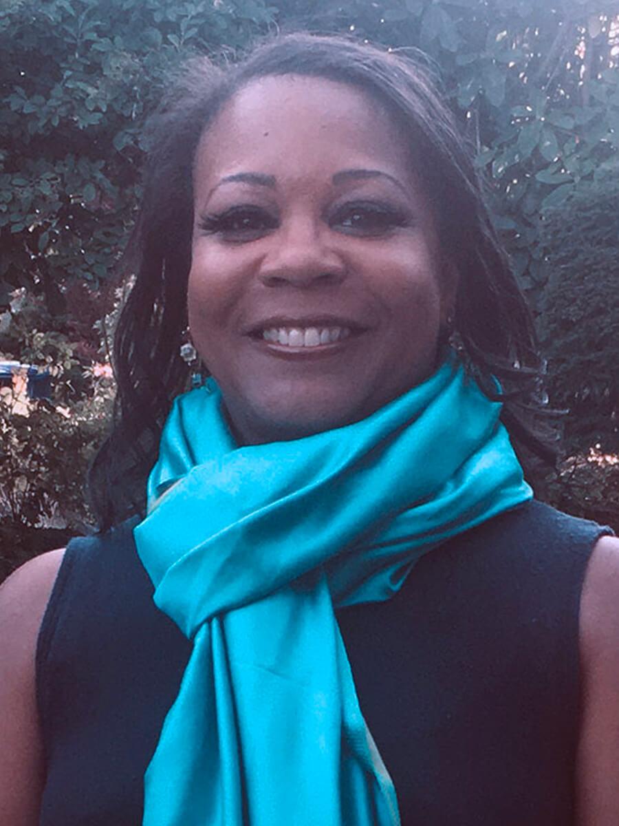 African American Woman with teal blue scarf smiling into camera with straight dark hair.