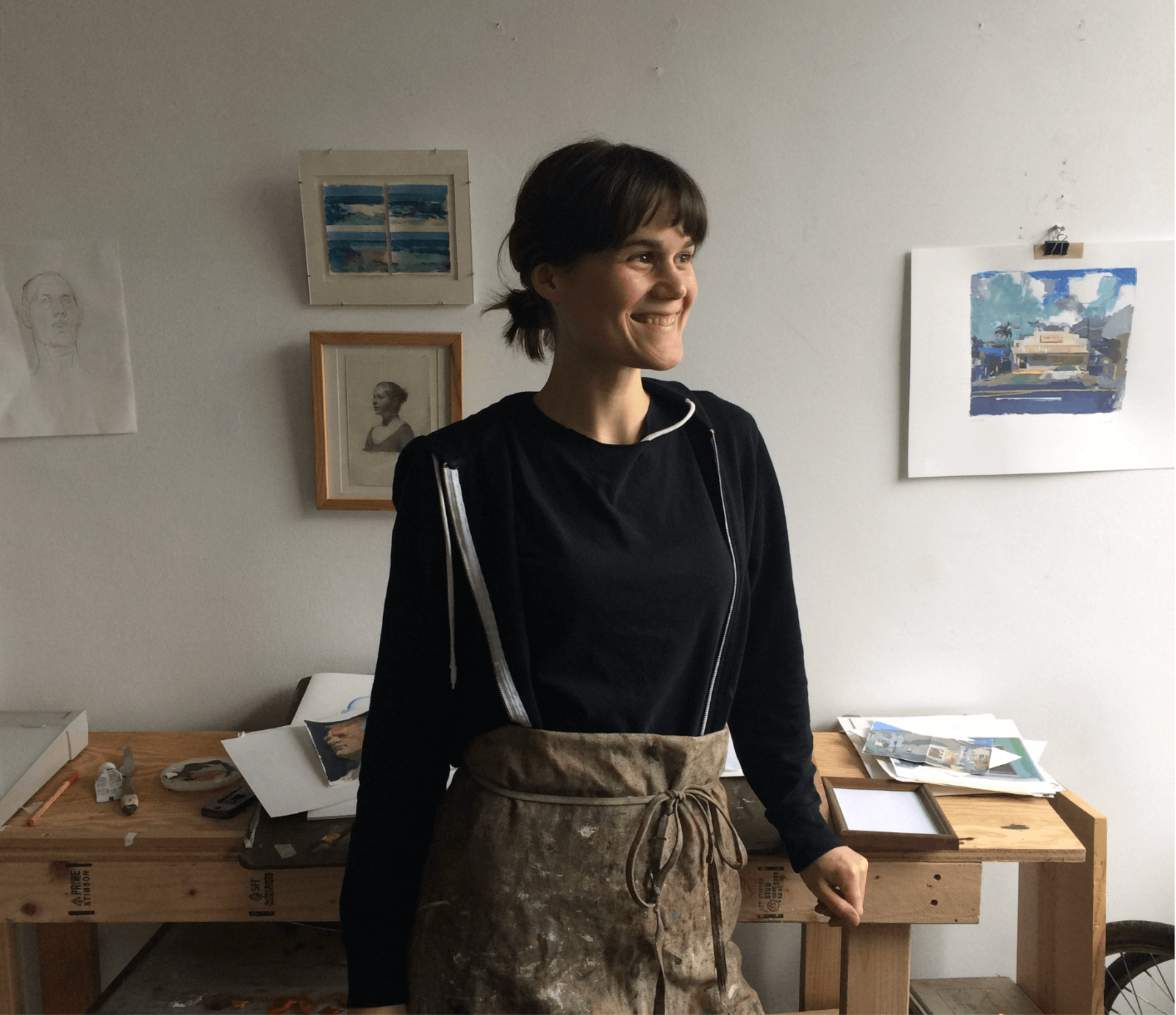 Sarah Bixler standing in a room with paintings on the wall. 