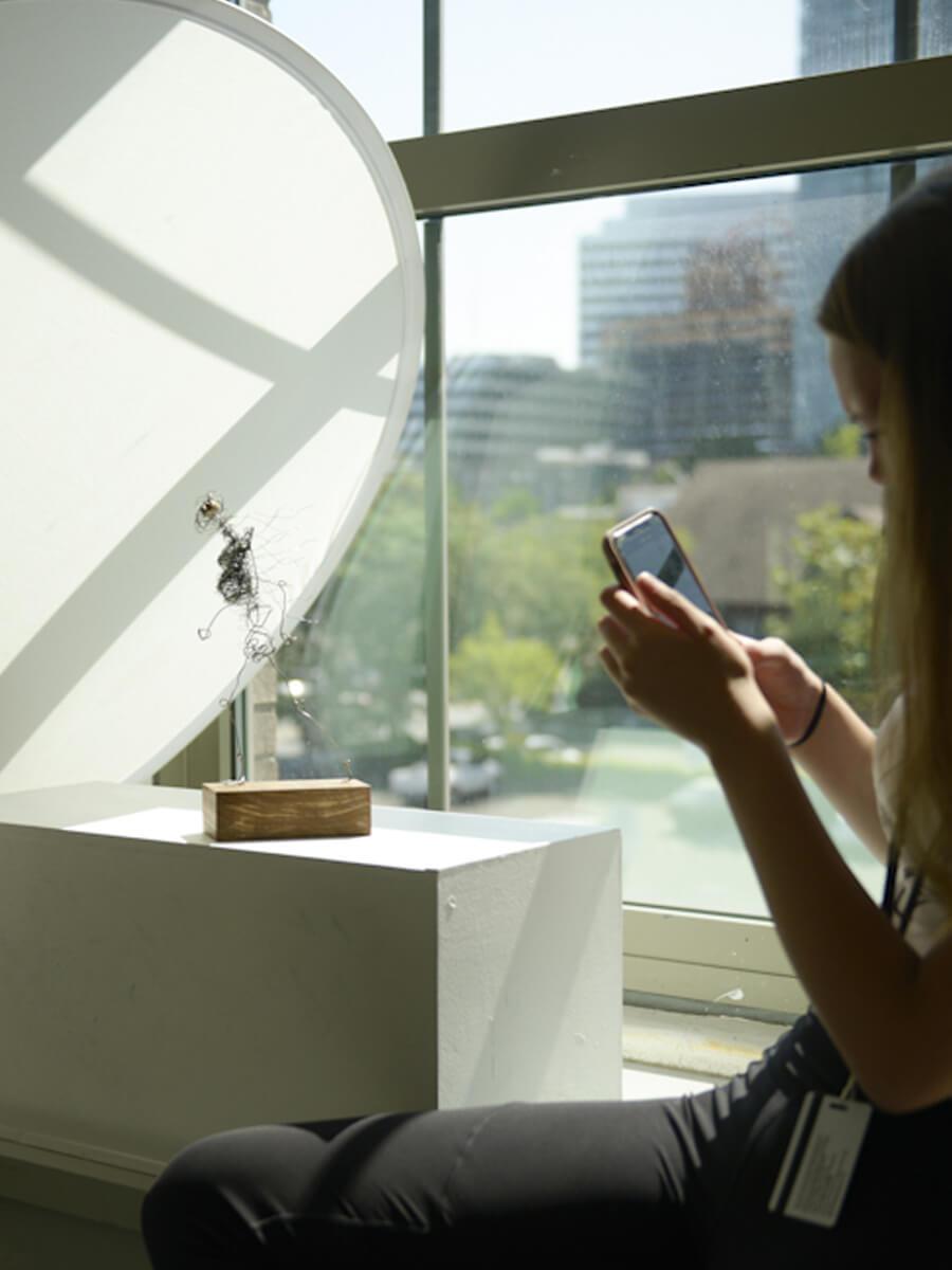 teenager taking a photo of sculptural artwork for portfolio