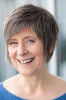 Diana Trotter with short hair and blue shirt smiling.