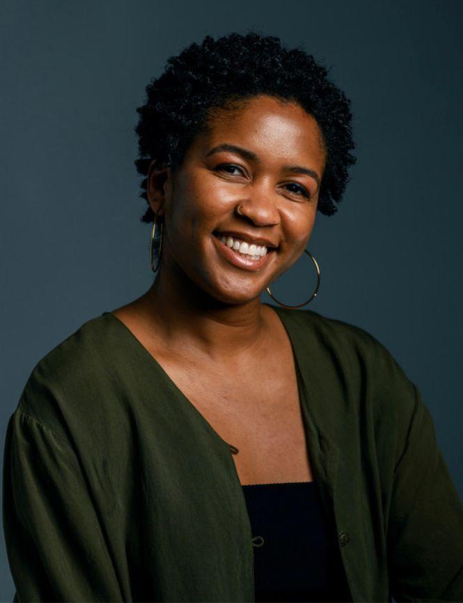 Nia-Amina Minor in a black sweater against a gray back ground